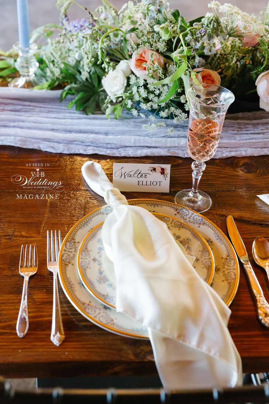 A table setting with plates , forks , knives , and a glass of wine.