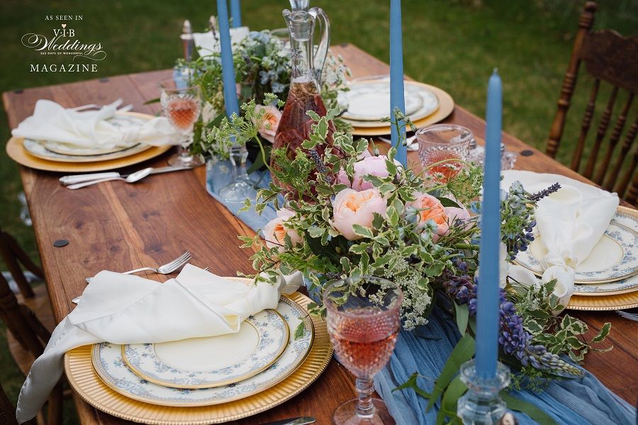 A wooden table with plates , candles , and flowers on it.