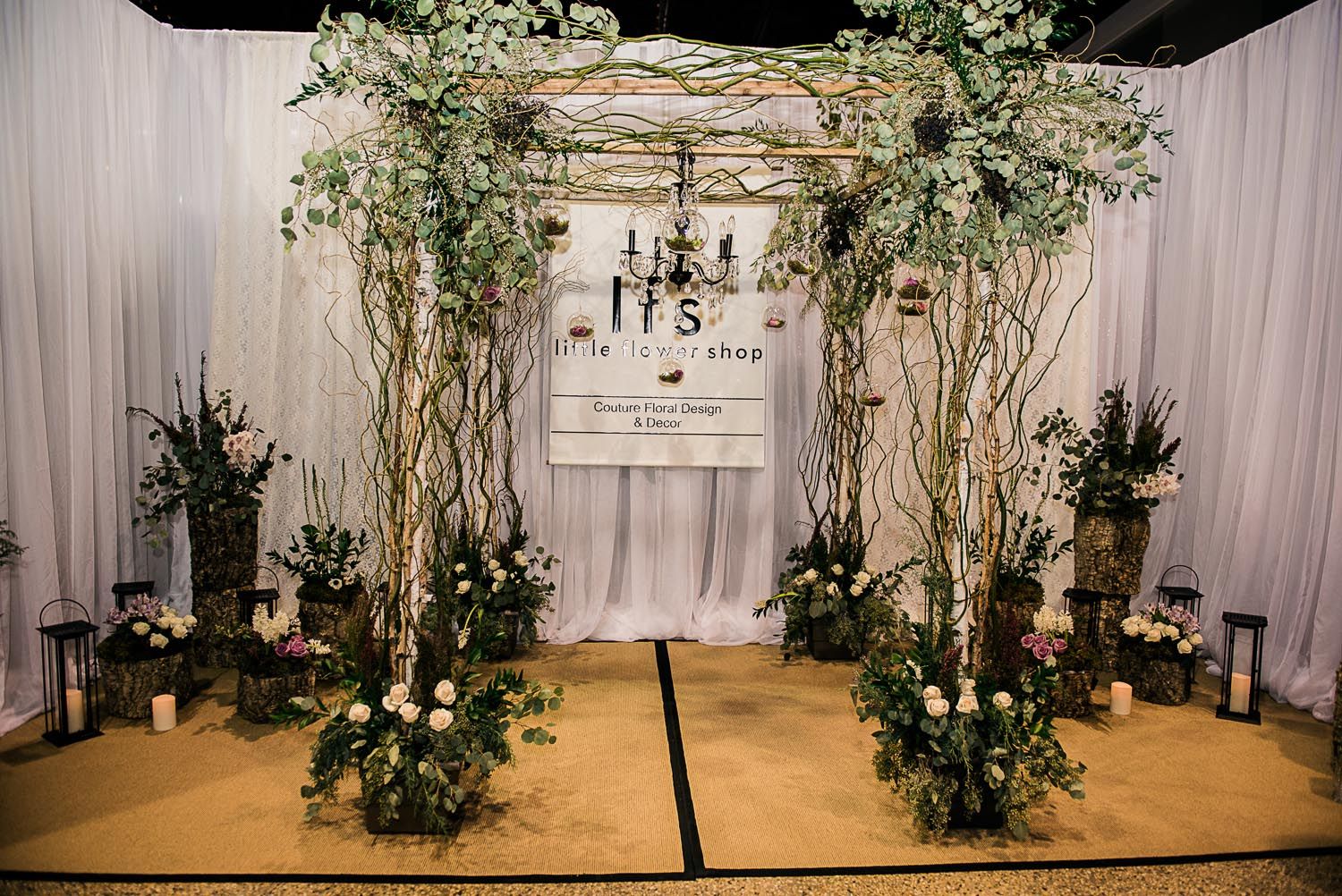 A wedding ceremony is being held in a room decorated with flowers and trees.