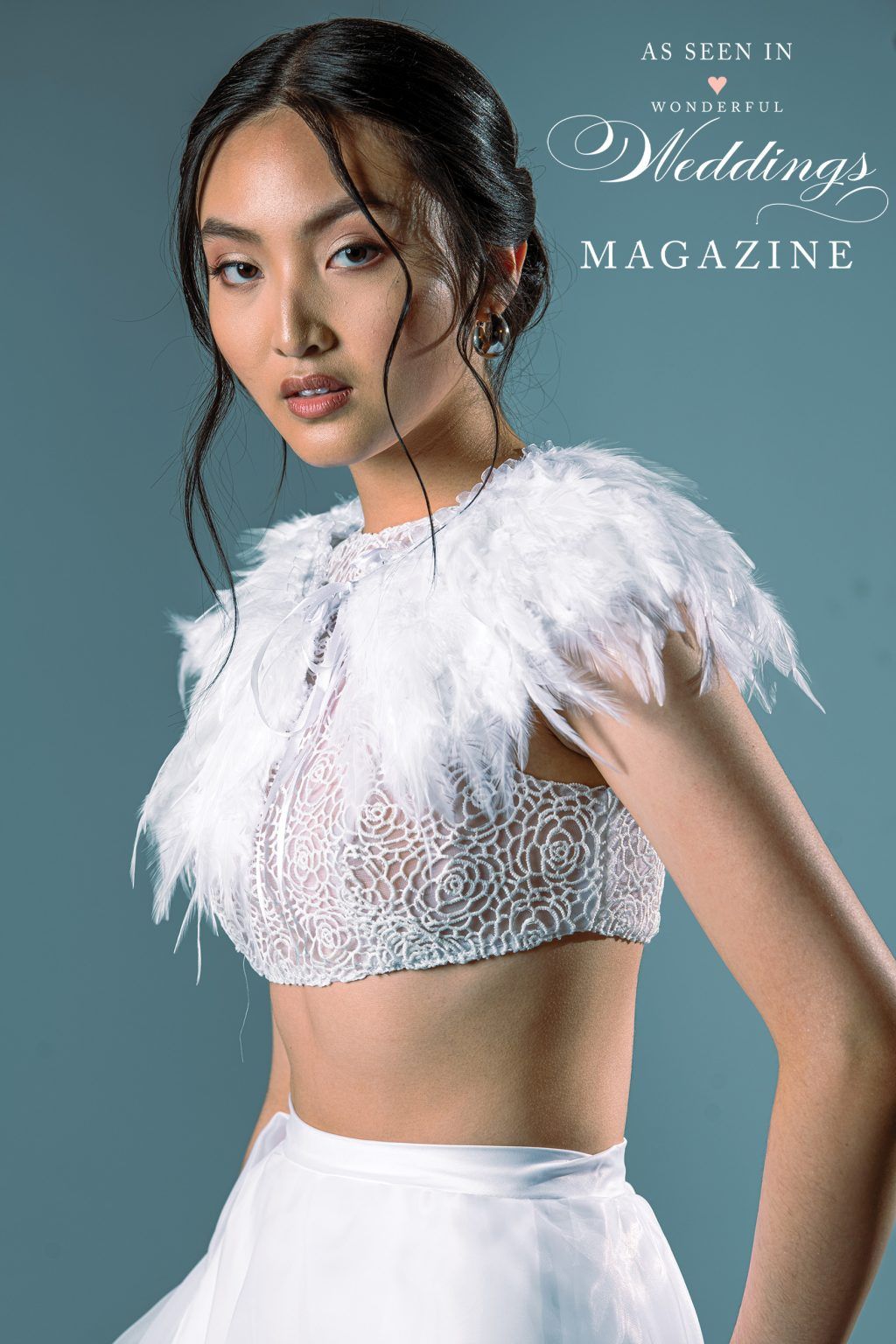 A woman in a wedding dress with feathers on her shoulder.