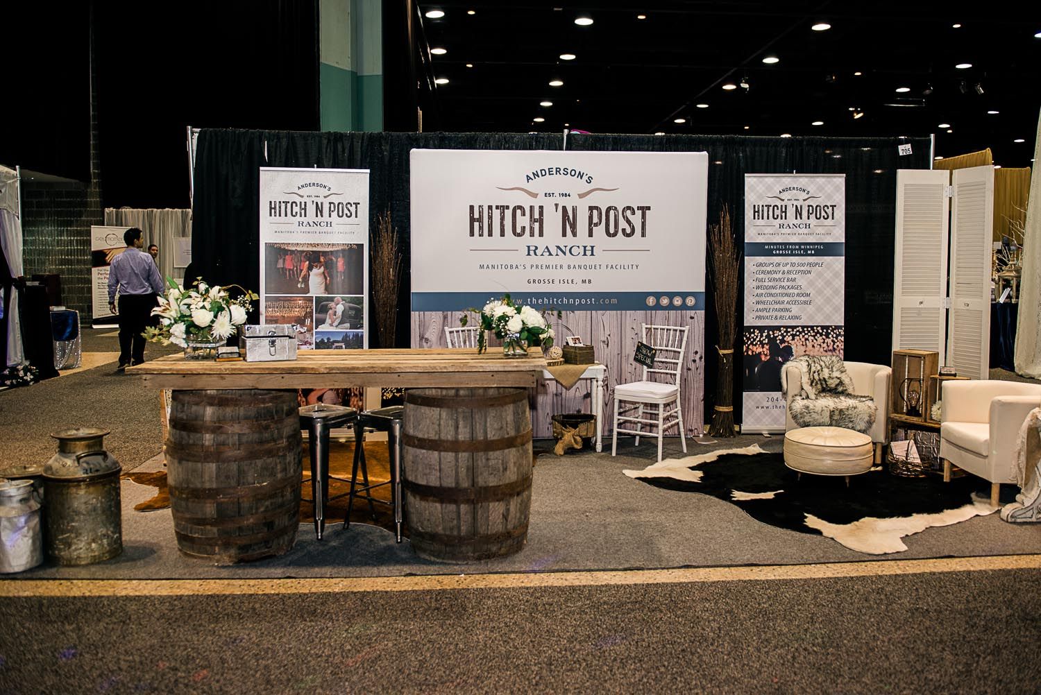 A booth with barrels , chairs , tables and a sign that says witch n post.