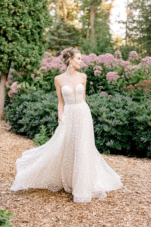 A woman in a wedding dress is standing in a garden.