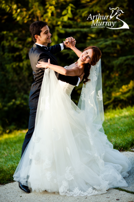 A bride and groom are dancing in a park.