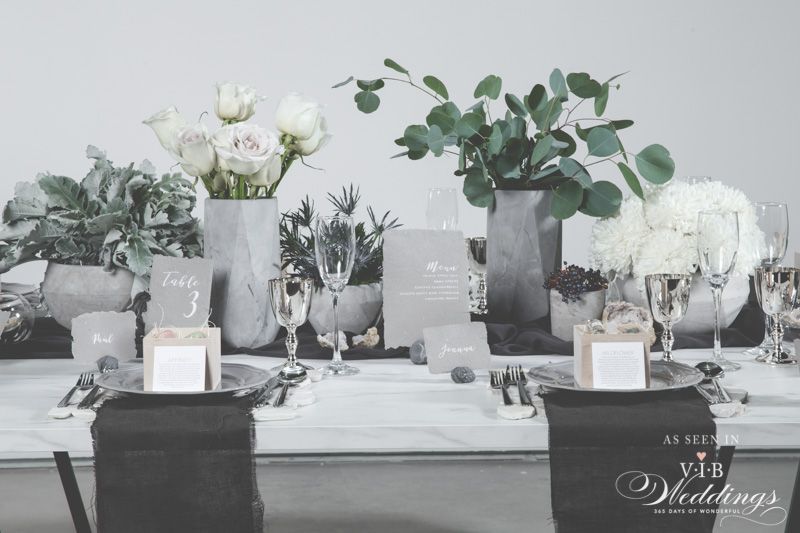 A table set for a wedding reception with flowers and glasses on it.