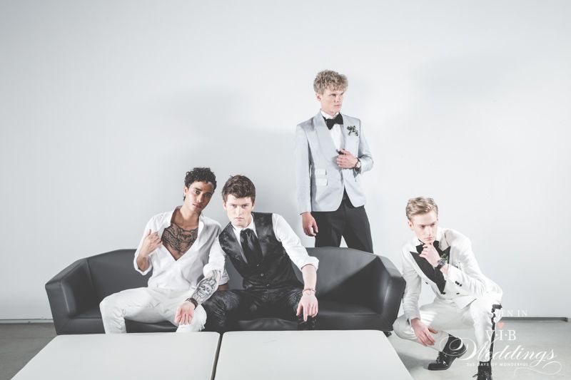 A group of men in tuxedos are sitting on a couch.
