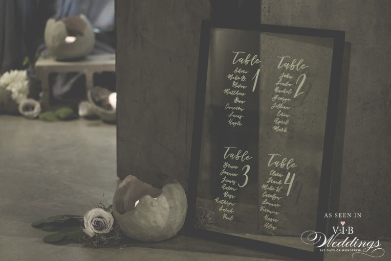 A table number sign is sitting on a table next to a vase of flowers.