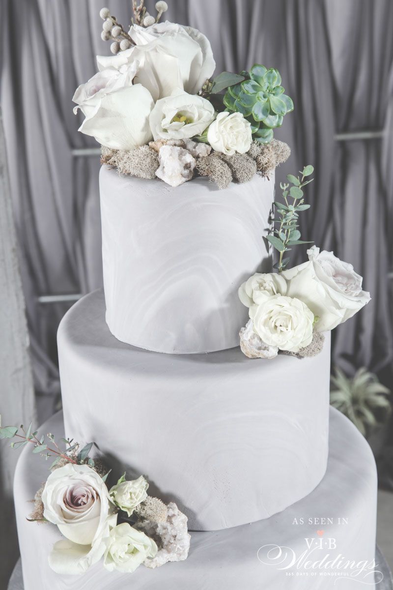 A white wedding cake with white flowers on top of it.