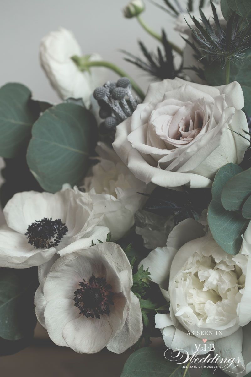 A close up of a bouquet of white flowers with green leaves.