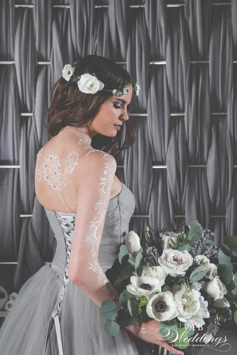 A woman in a gray dress is holding a bouquet of flowers.