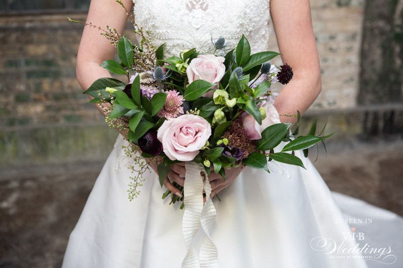 A bride in a wedding dress is holding a bouquet of flowers.
