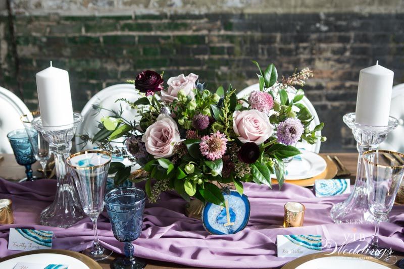 A table with plates , glasses , candles and flowers on it.