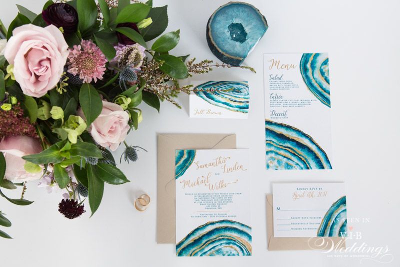 A wedding invitation is sitting on a table next to a bouquet of flowers.