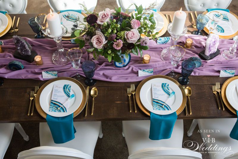 A table set for a wedding reception with plates , napkins , and candles.