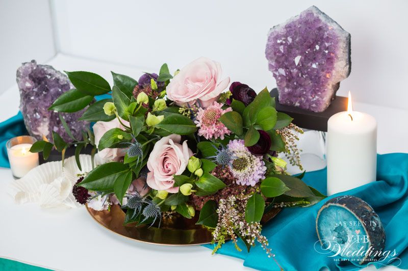 A table with flowers , candles , and crystals on it.