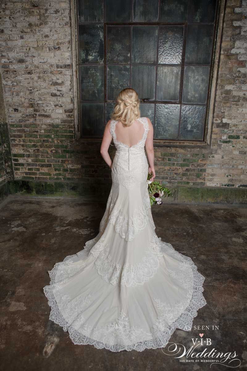 A woman in a wedding dress is standing in front of a brick wall.