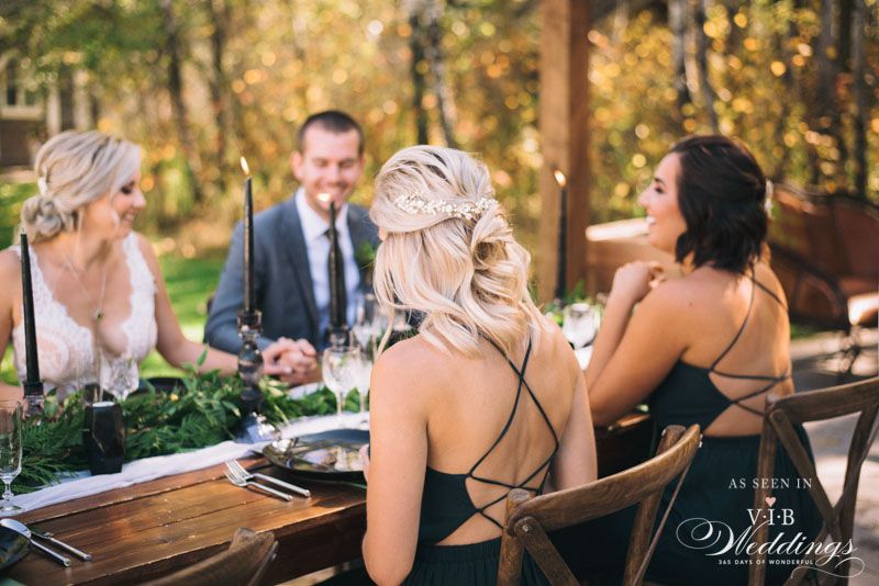 A bride and groom are sitting at a table with their bridesmaids.