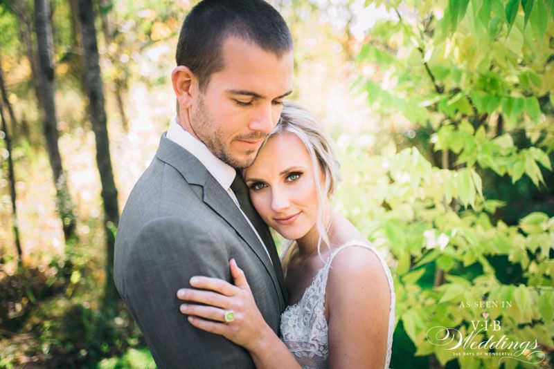 A bride and groom are posing for a picture in the woods.