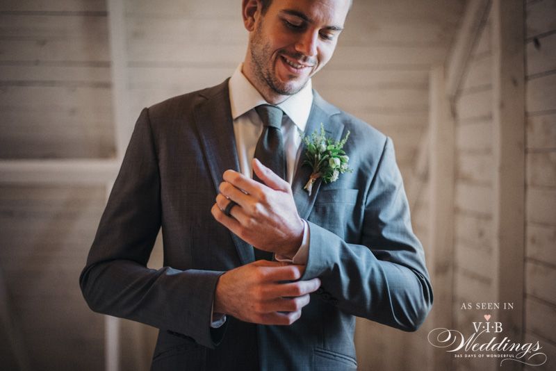 A man in a suit and tie is adjusting his cufflinks.