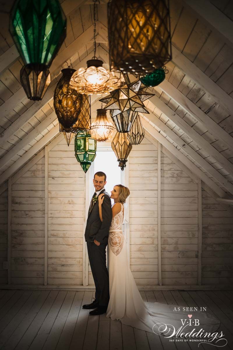 A bride and groom are posing for a picture in a room with lanterns hanging from the ceiling.