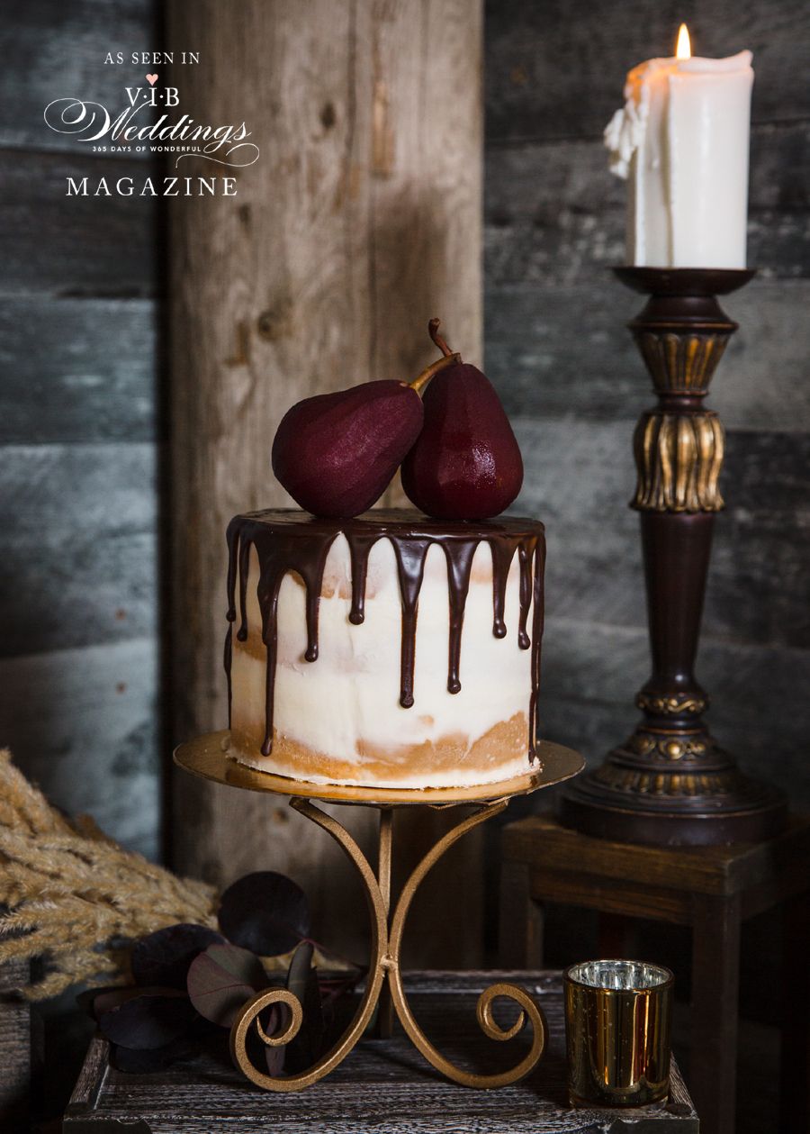 A cake with pears on top of it is sitting on a table next to a candle holder.