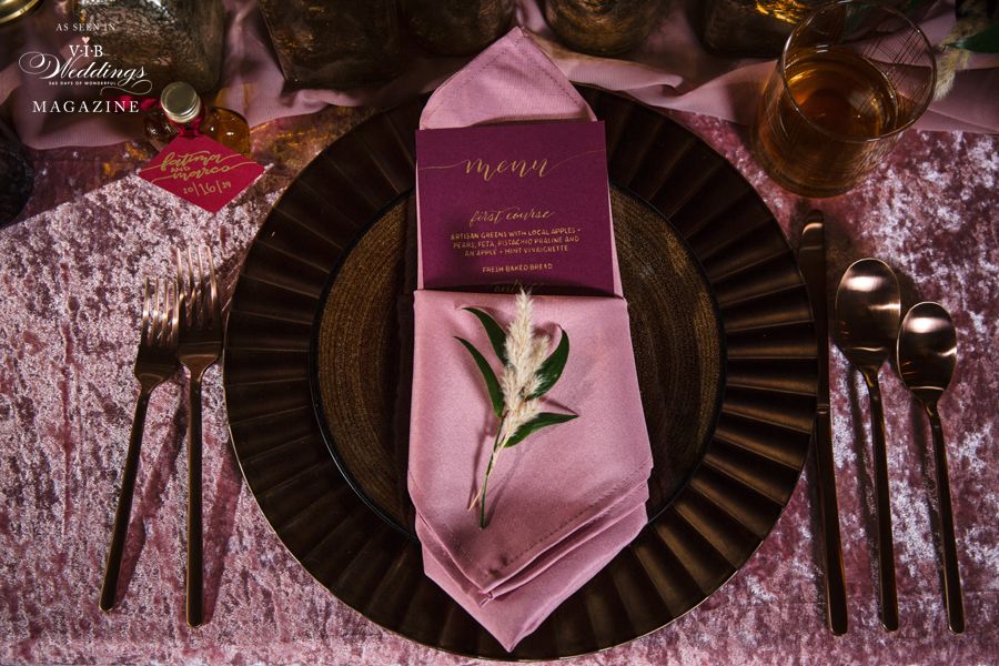 A place setting with a pink napkin and a menu on it