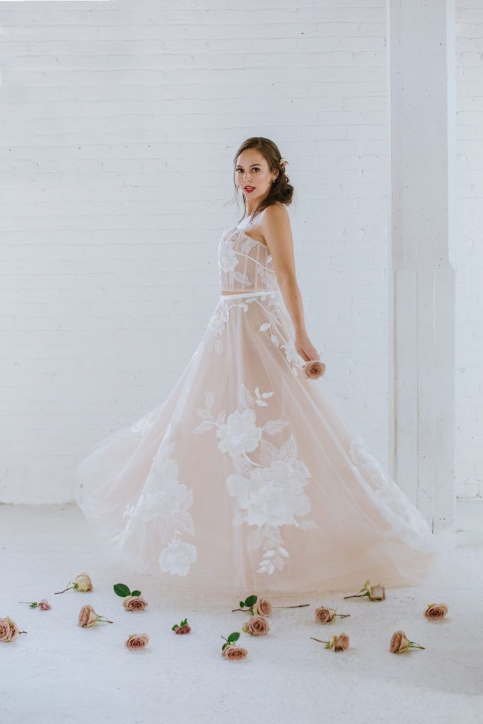 A woman in a wedding dress is standing in a room surrounded by flowers.