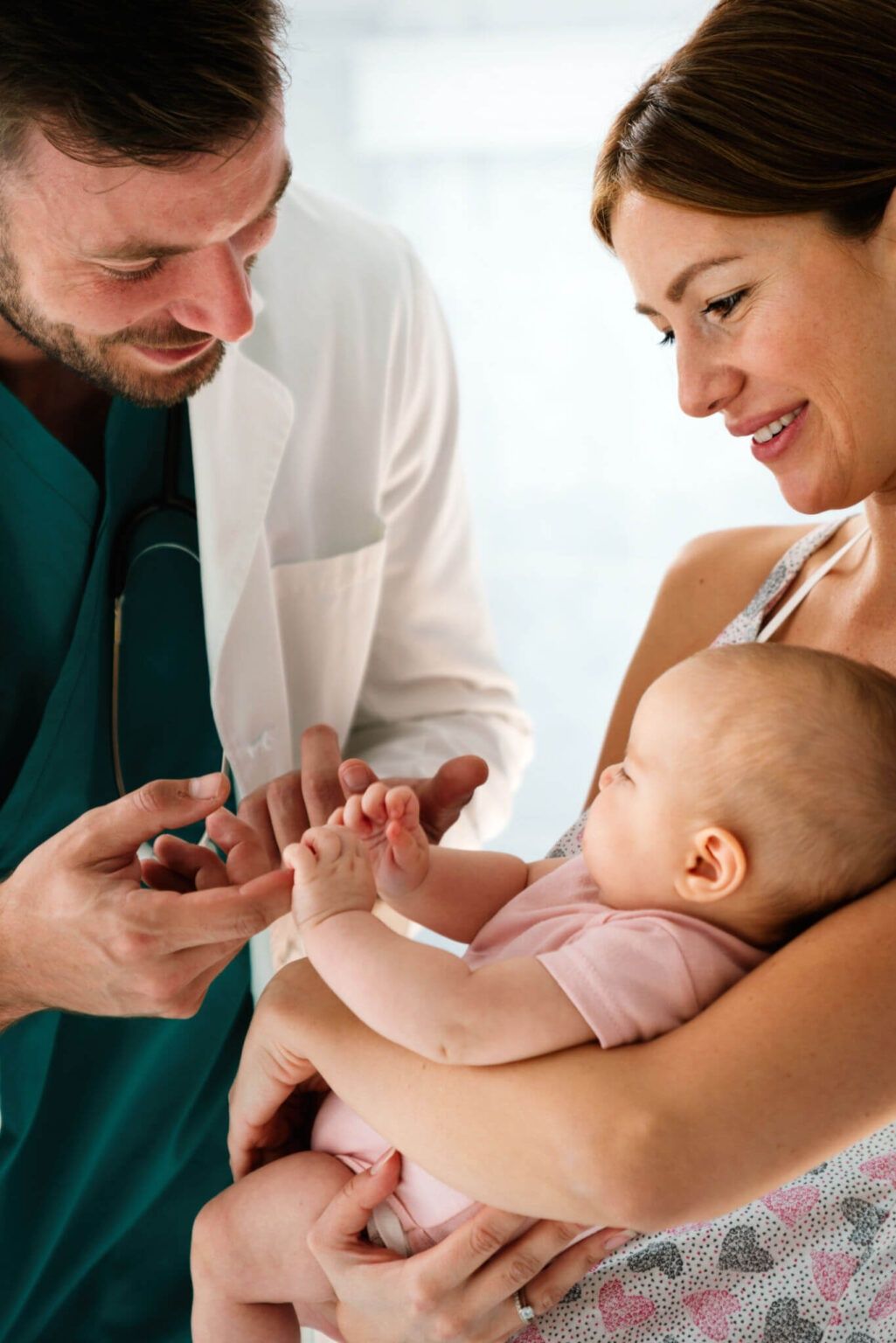 Doctor examining a smiling baby while a mother holds the child