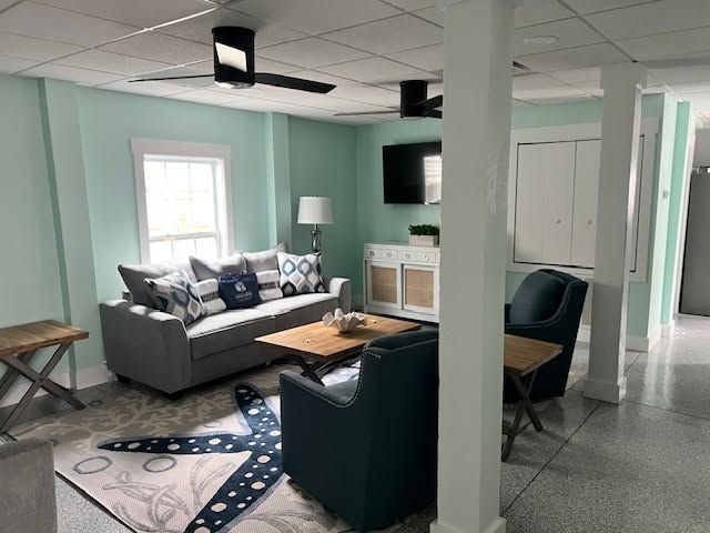 Bright teal living room with gray sofa, black chairs, coffee table, and wall-mounted TV