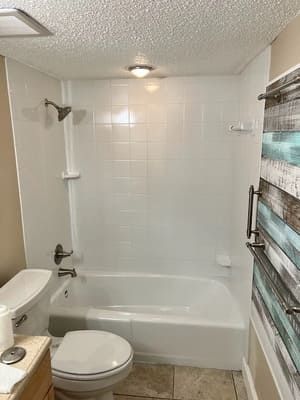 Compact white bathroom with tub-shower, toilet, sink edge, and striped shower curtain.