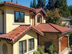 Mediterranean-style house with red tile roof, stone accents, and garage under a clear blue sky