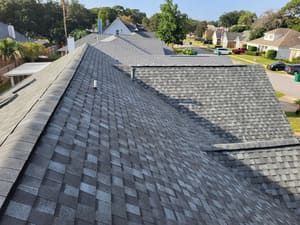 Roof shingles on a house, viewed from above on a suburban street.