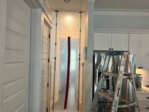 Interior hallway with a ladder and a hanging red strip in a bright kitchen area