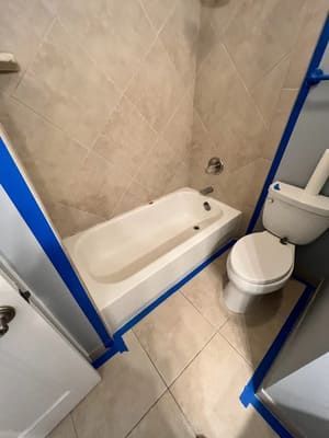 Small bathroom with a tub, toilet, and shower area outlined with blue tape.