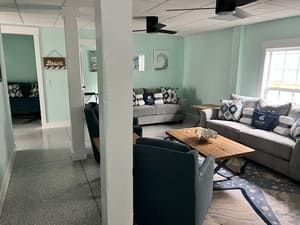 Bright living room with gray sofas, blue chairs, a wooden coffee table, and mint walls