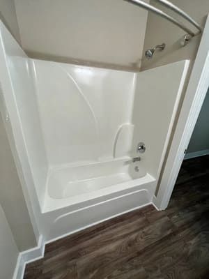 White bathtub and shower combo with curved curtain rod and built-in seat in a bathroom.