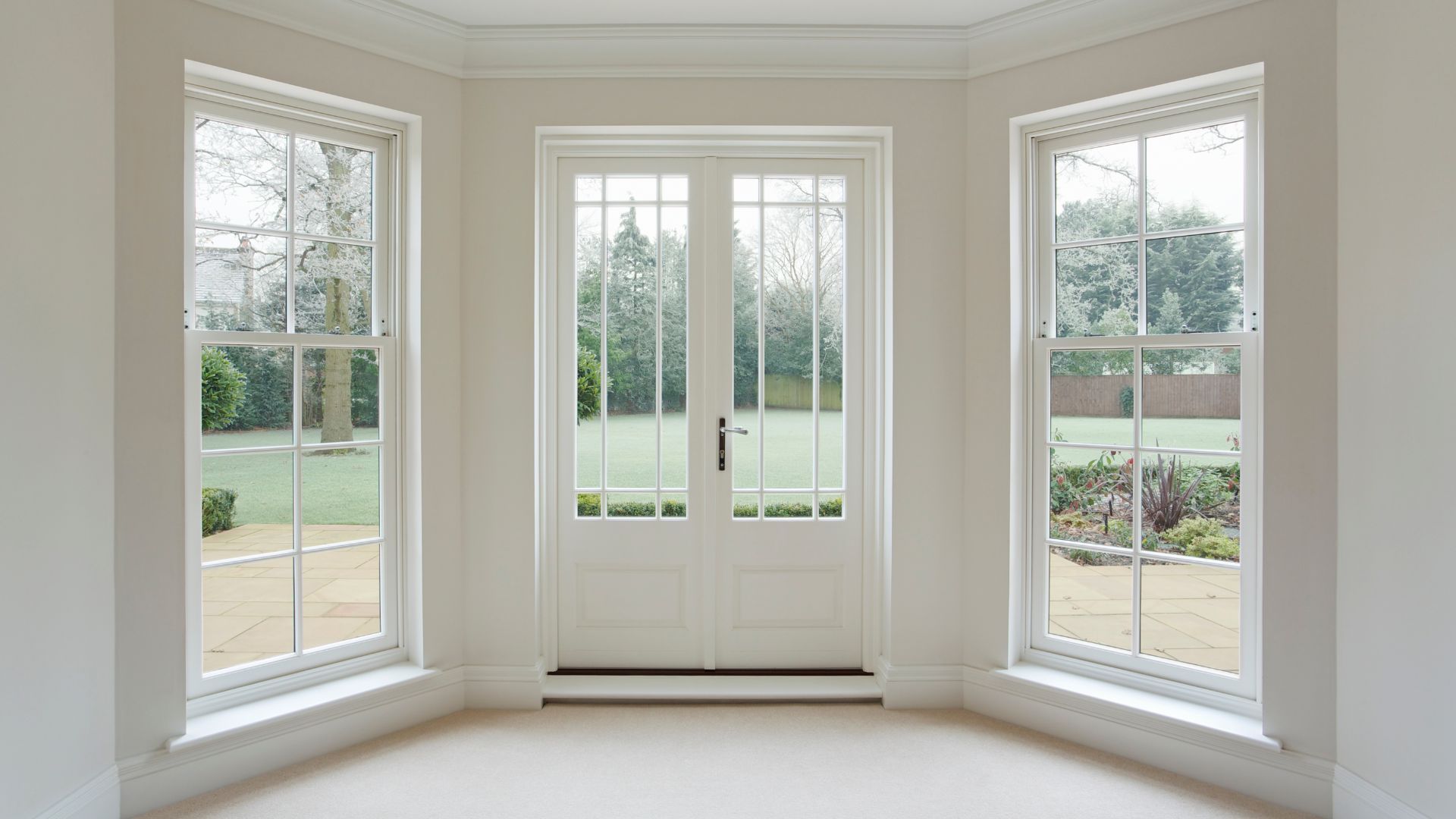 Bright bay window nook with white French doors overlooking a green yard