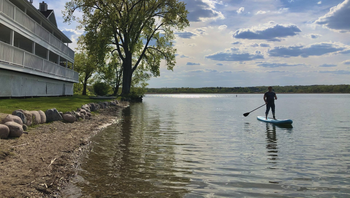 A man is standing on a paddle board in the water.