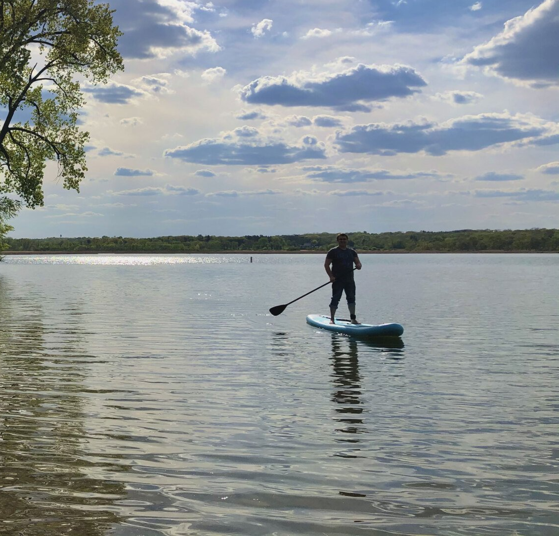 A man is standing on a paddle board in the water