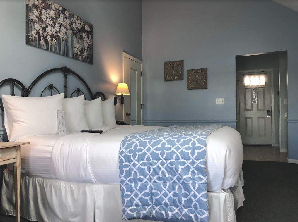 A hotel room with a king size bed and a blue blanket