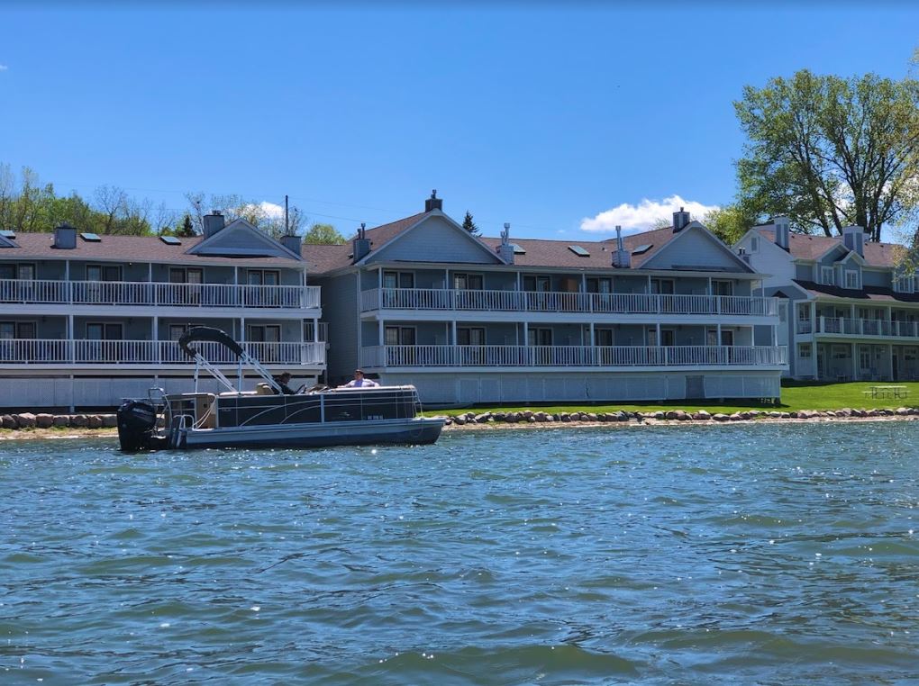 A pontoon boat is floating on a lake in front of a building.