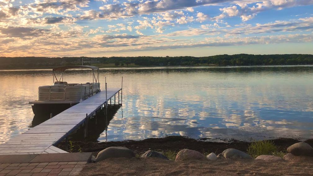 A boat is docked at a dock on a lake at sunset.