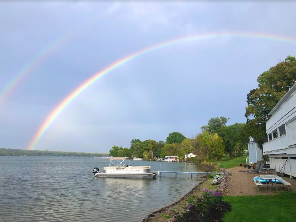 A rainbow over a lake with a boat in the water