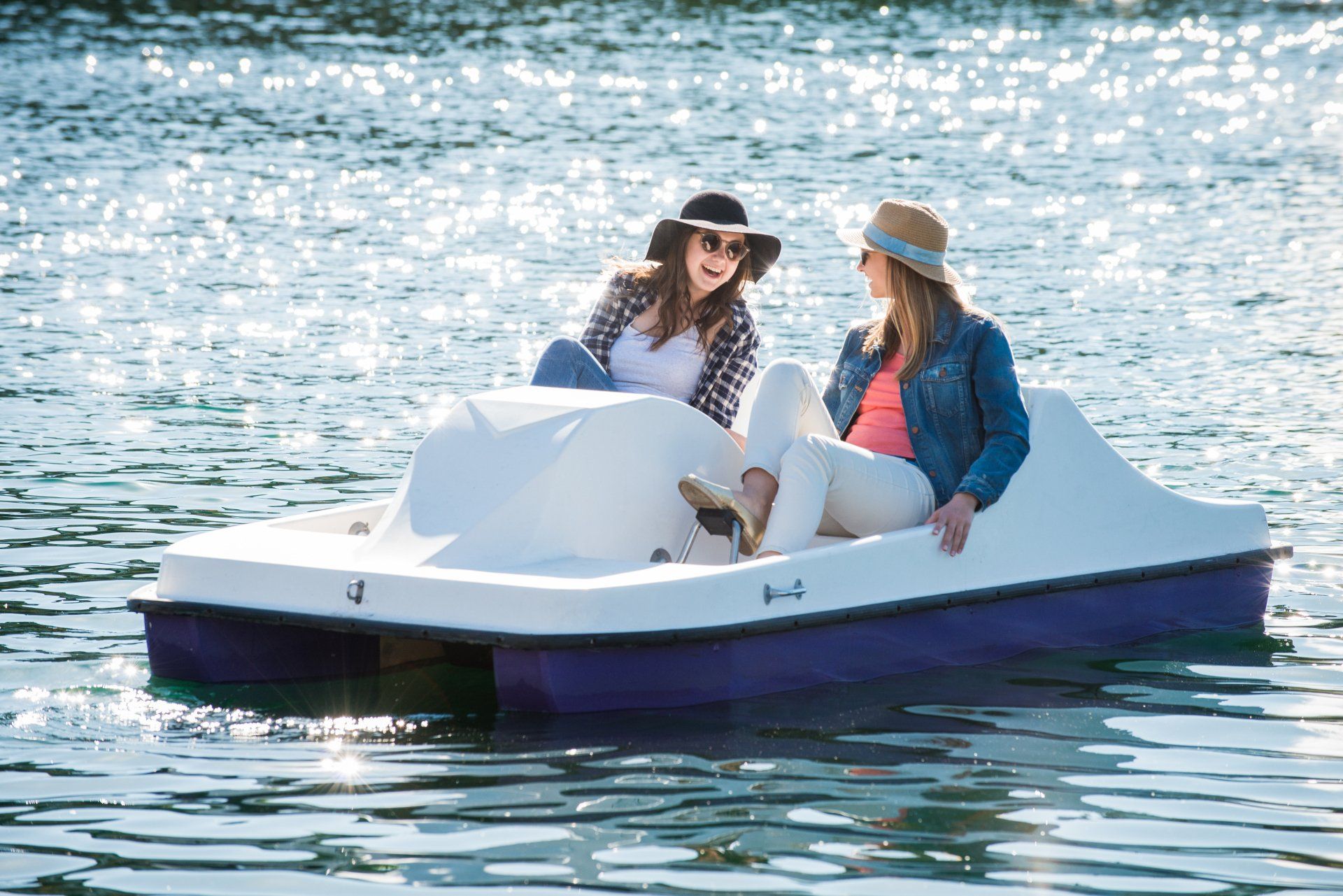 Two women are riding a pedal boat on a lake.