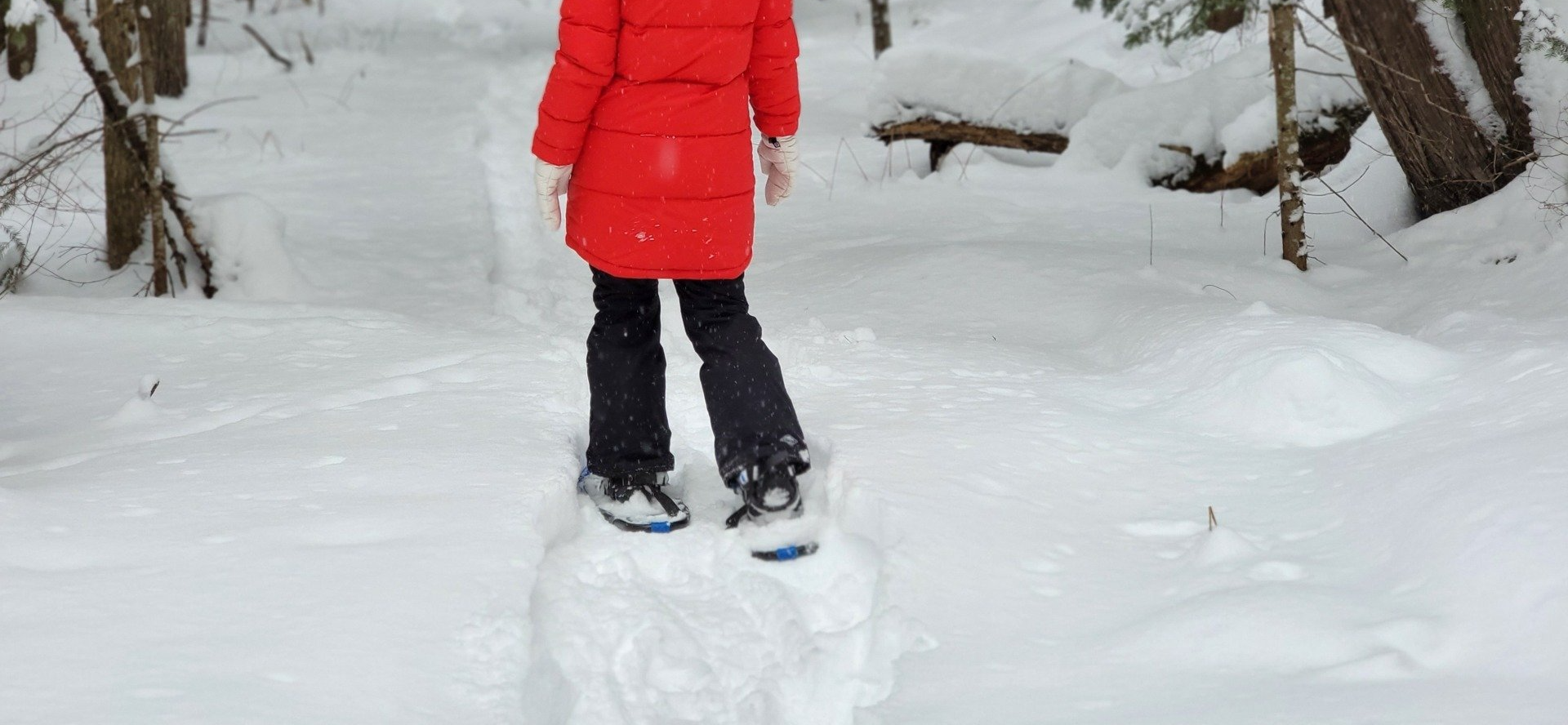 A person in a red coat is standing on top of a pile of snow.