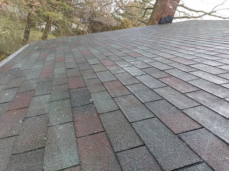 A close up of a roof with a chimney and trees in the background.