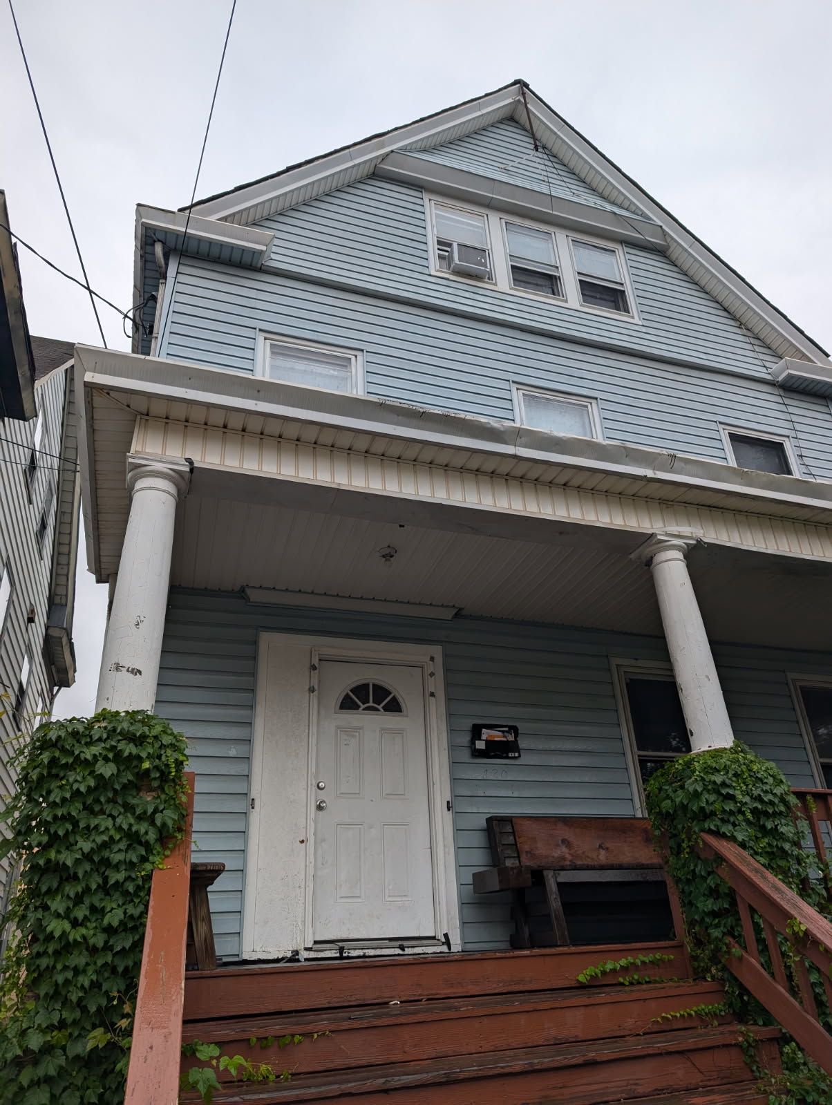 Blue house with white porch columns, front door, and red steps viewed from below
