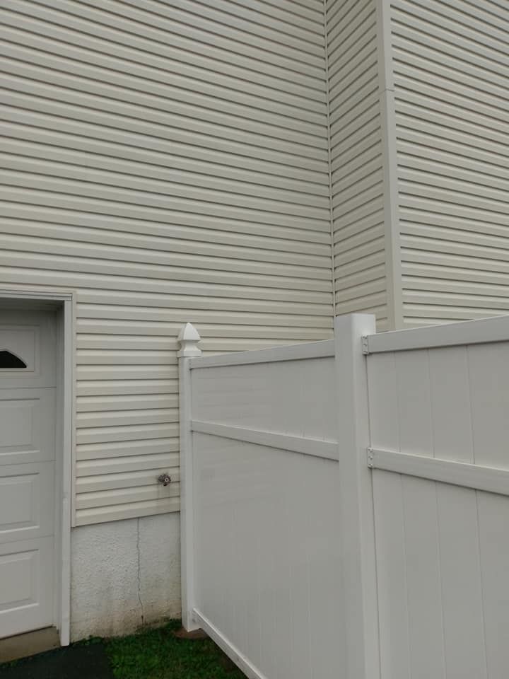 A white fence is in front of a white house.