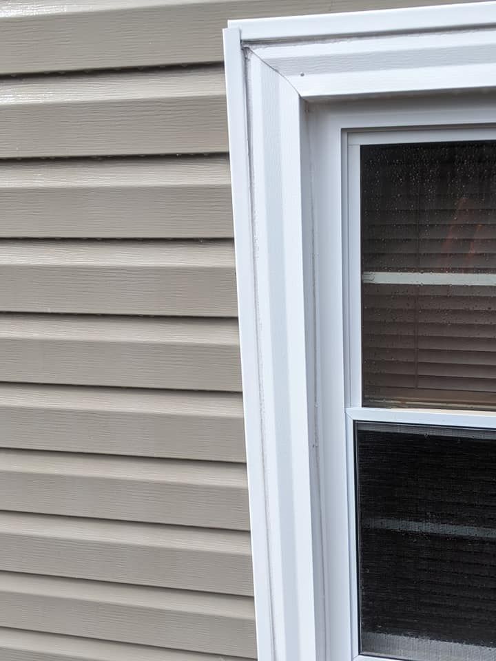 A window with a white frame is on the side of a house