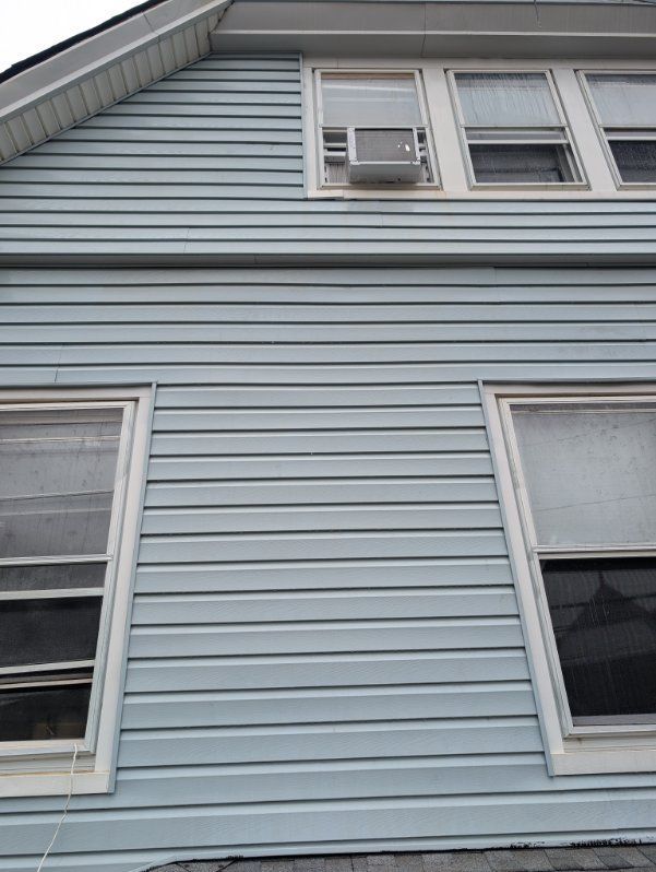Blue house exterior with white-trimmed windows and an air conditioner unit