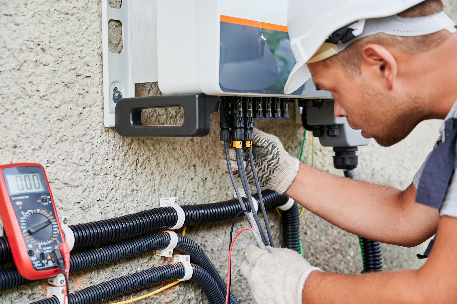 A man is working on a generator panel with a multimeter.